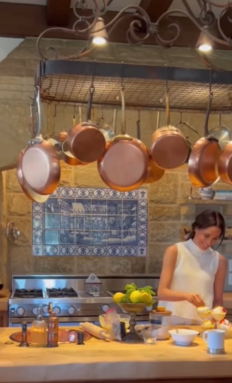 Meghan Markle smiles as she bakes cake in her kitchen with her pots and kitchen utensils on full display