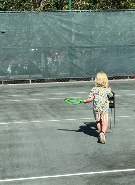 boy with green tennis racket on court