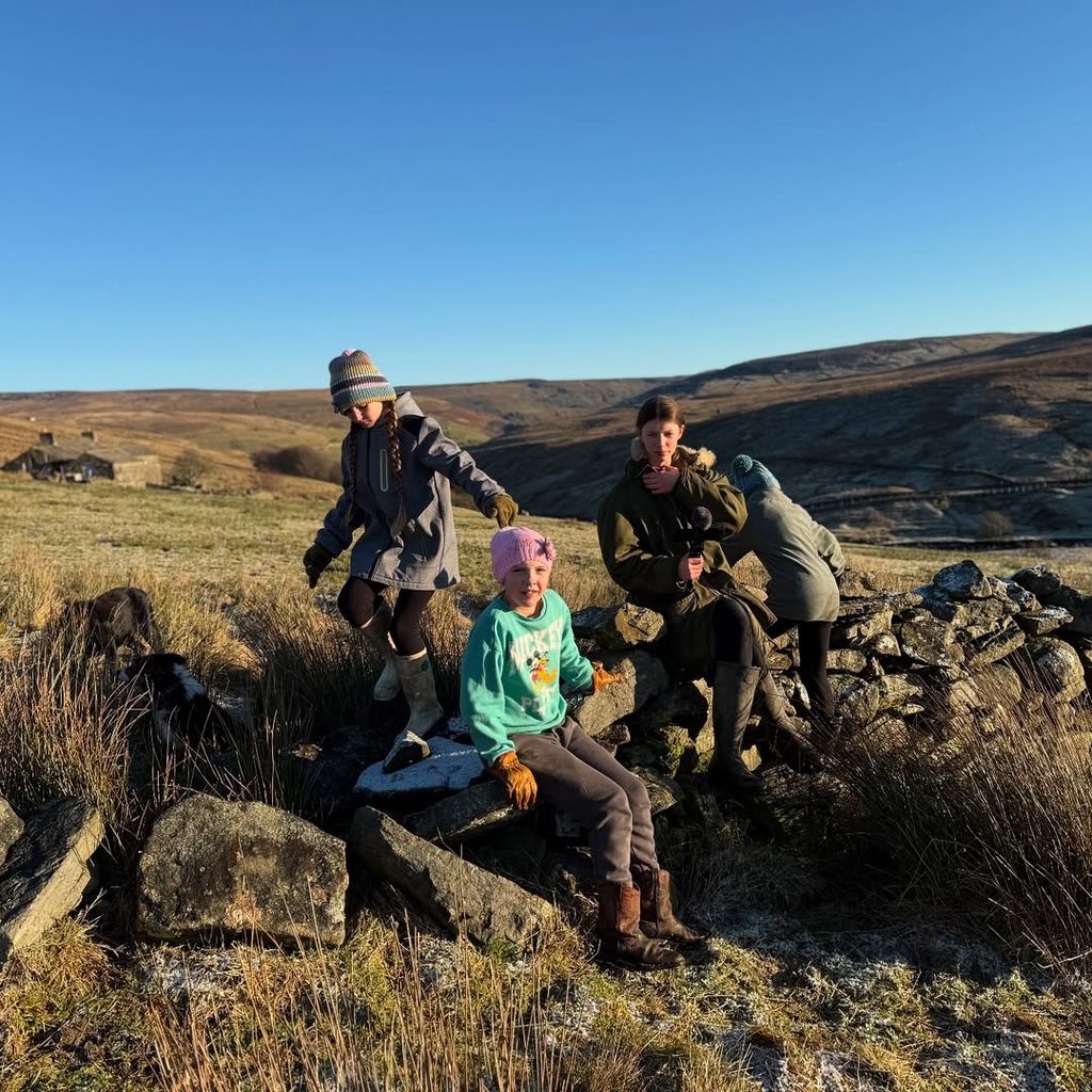 Four of Amanda Owen's children with sitting on rocks with hills in the background at their farm in Yorkshire