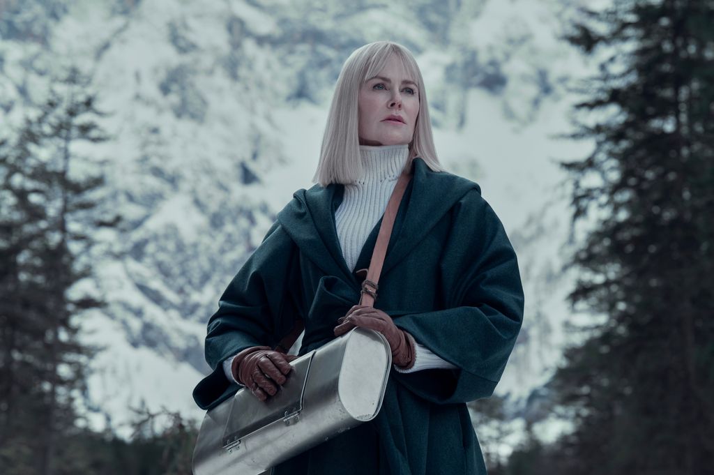 woman with blonde hair standing in front of snowy trees