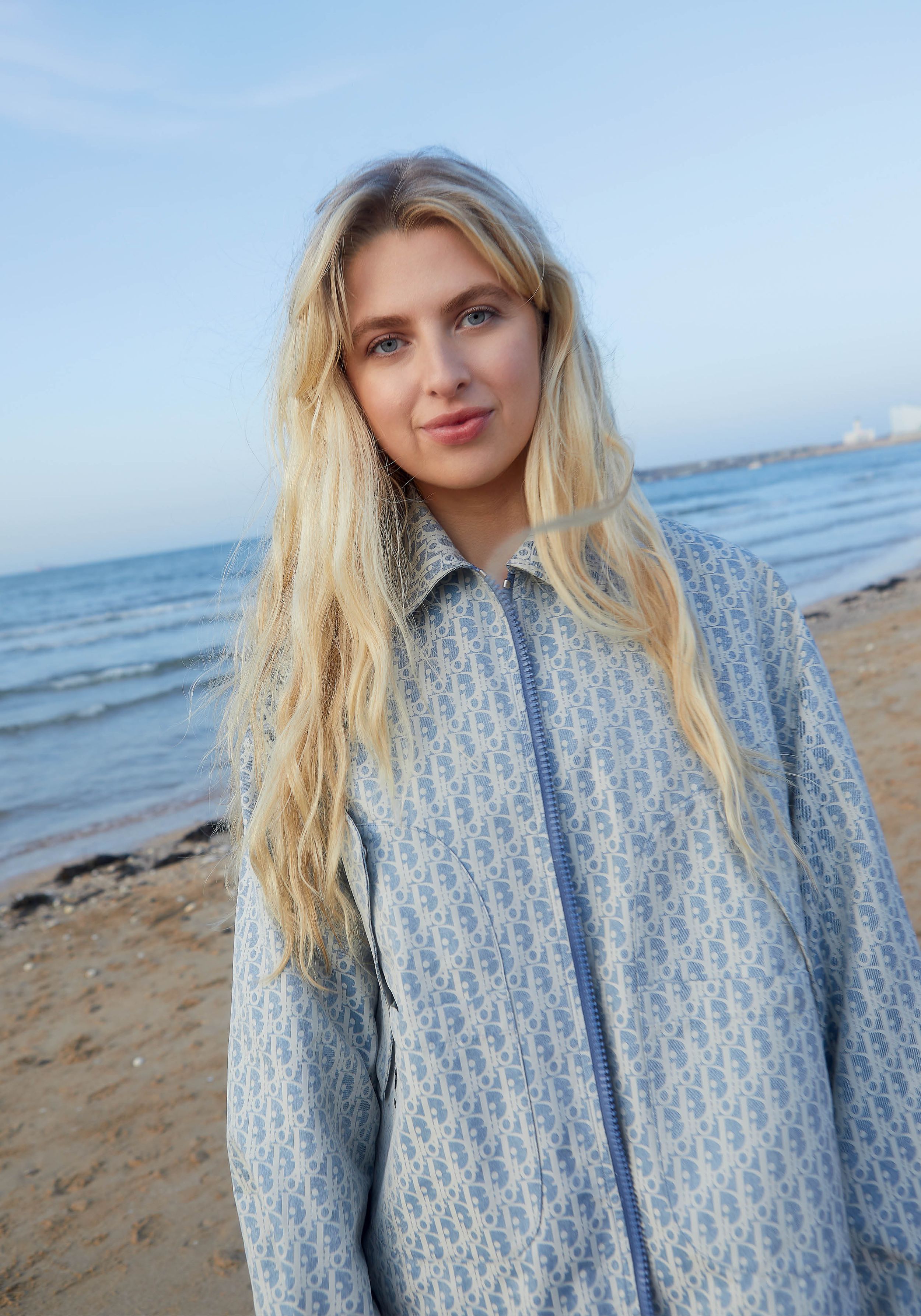 Anaïs Gallagher poses on the beach wearing a Dior coat