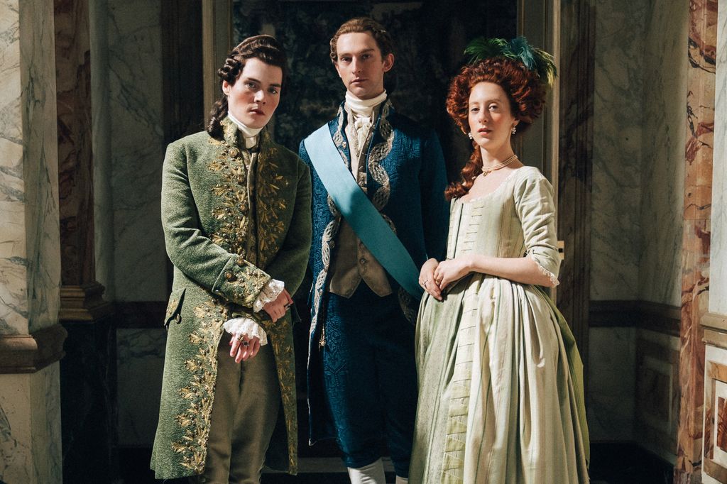 two men and woman in period clothing standing in hallway
