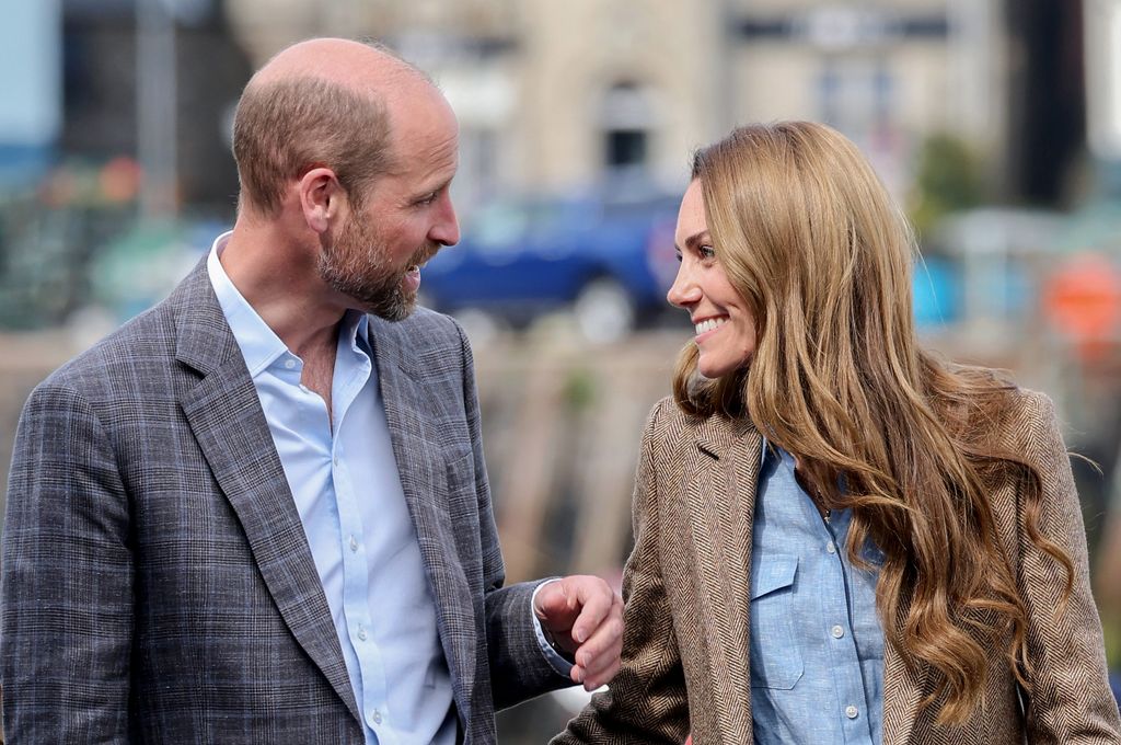 Princess Kate with long curled hair looking at Prince William
