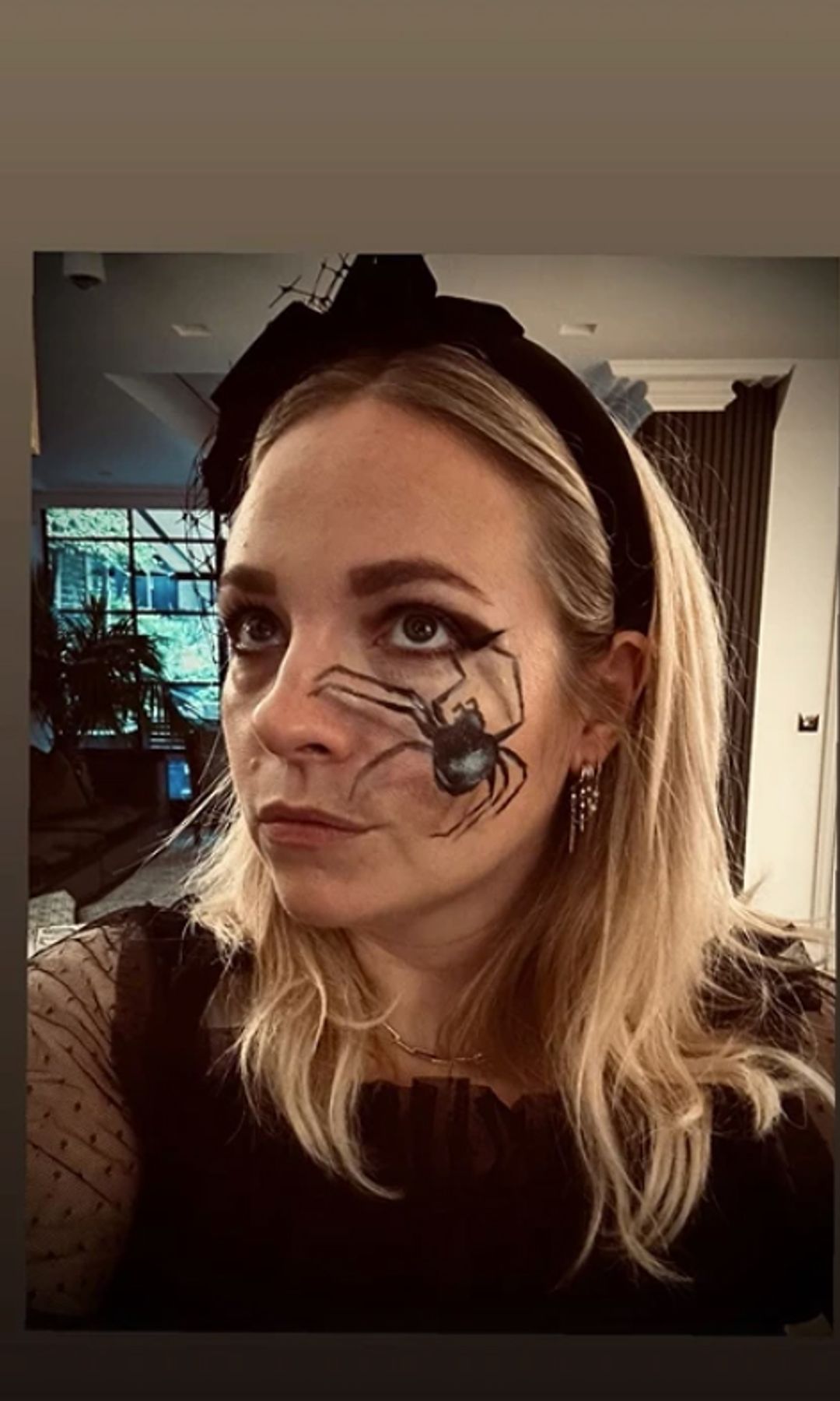 Georgia Tennant in her livign room with a spider decoration on her cheek