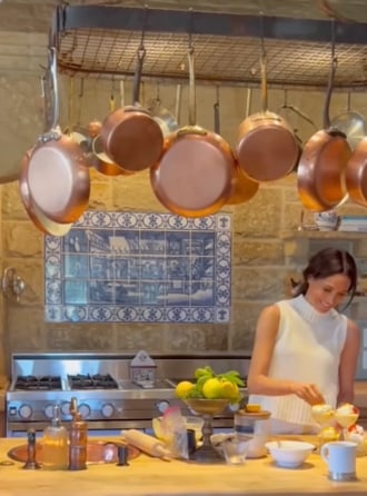 Meghan markle cooking in family kitchen with saucepans hanging up