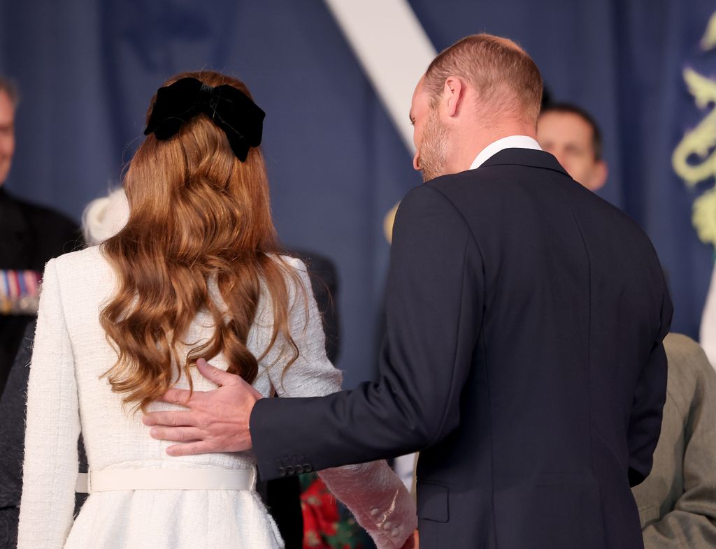 William with his hand on Kate's back at VE Day concert