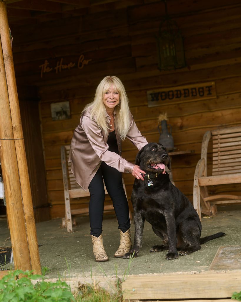 jo wood leaning down to stroke her black dog