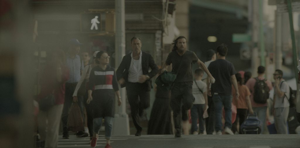 two men running across busy street in city