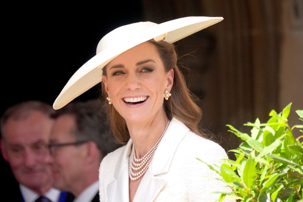 Catherine, Princess of Wales smiling shoulders up in white dress and hat