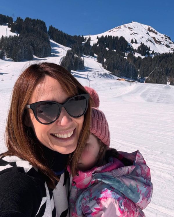 Alex Jones smiling while hugging her daughter