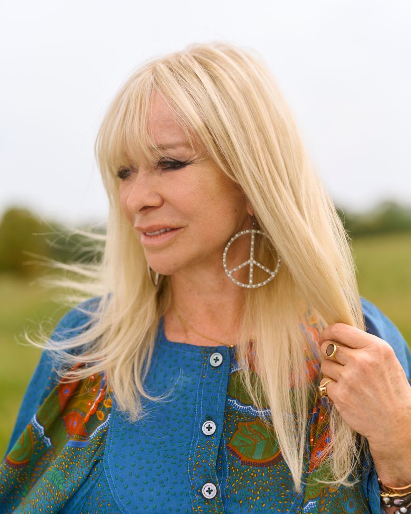 Jo Wood with peace sign earrings looking pensive 