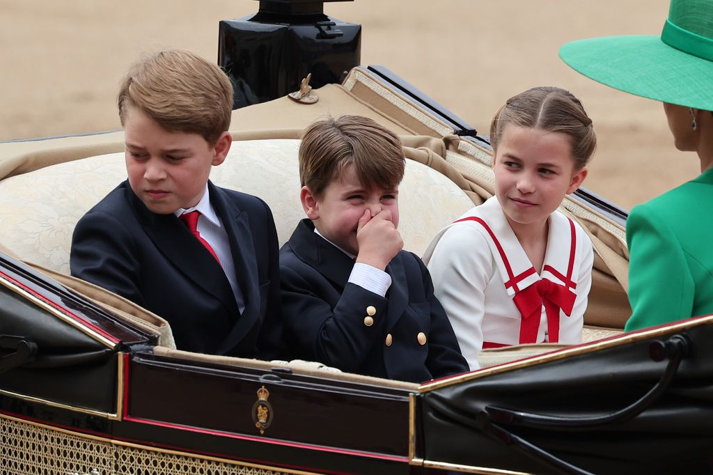 Prince Louis holding his nose in a carriage next to Princess Charlotte and Prince Louis