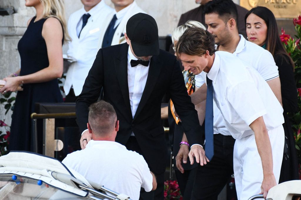 A photo of a man in a suit and bow tie getting into a boat