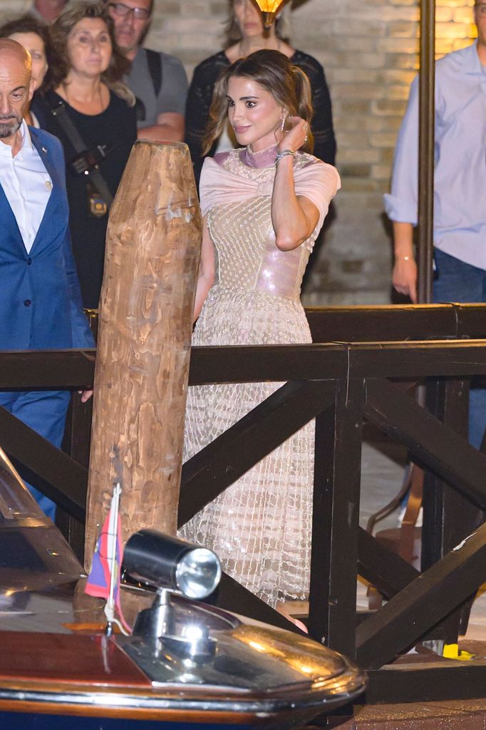 Queen Rania wears a blush pink gown featuring a sequin-embellished skirt and satin draped neckline, accessorised with a soft updo and diamond jewellery.