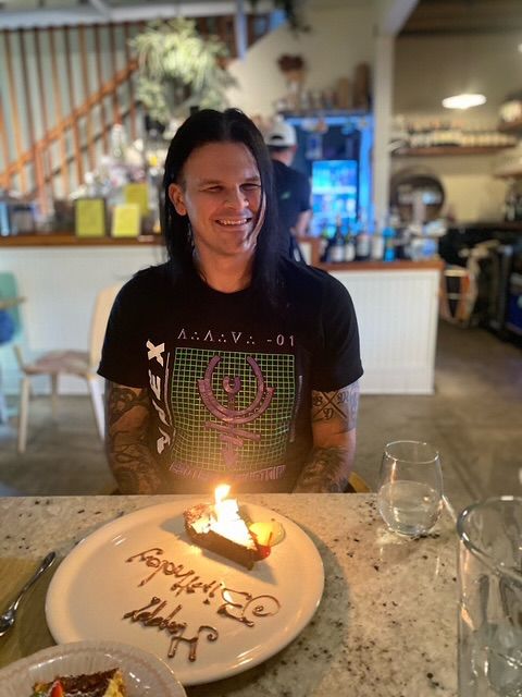 Travis Bacon poses for a photo inside his family home with a slice of birthday cake, shared on Instagram