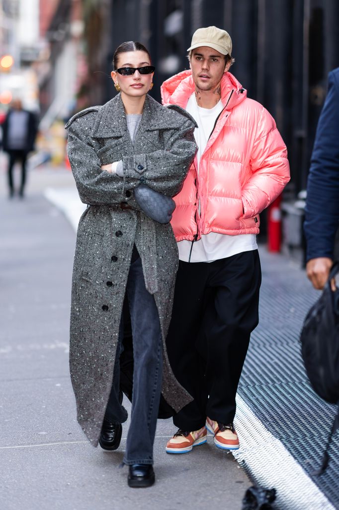 Hailey Bieber walking with her arms folded and Justin closely behind walking through NYC