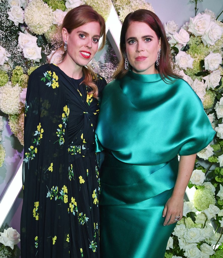 Beatrice and Eugenie wearing evening dresses in front of a flower wall