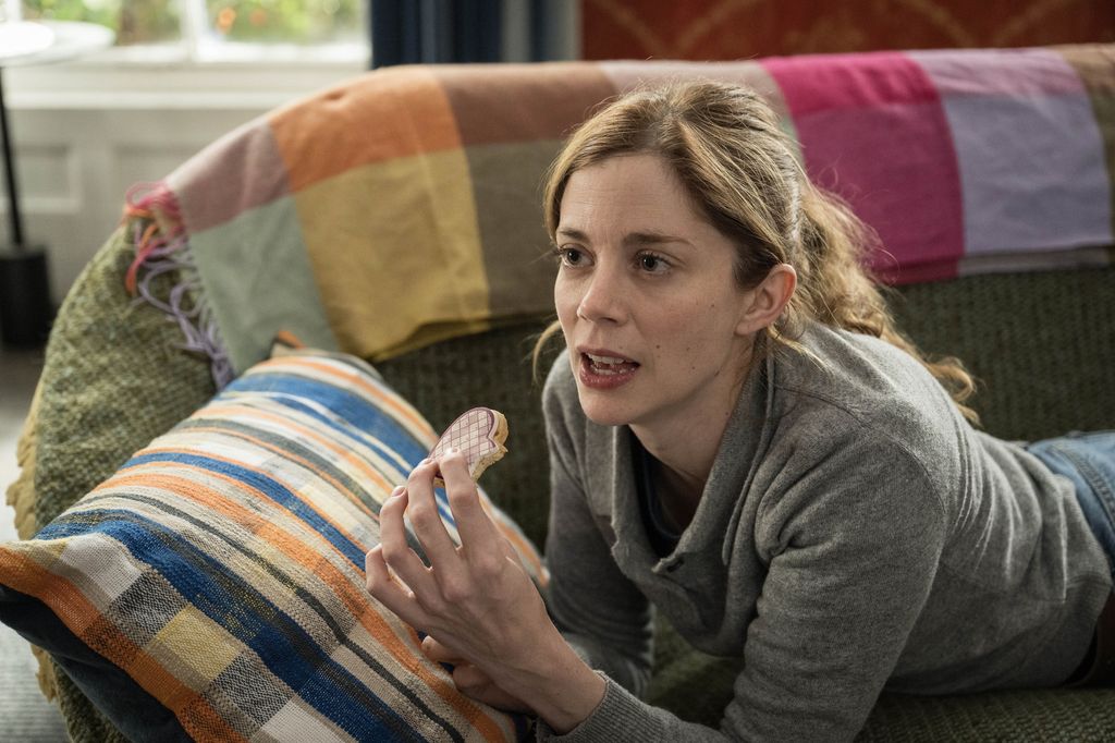 young woman eating biscuit lying on sofa