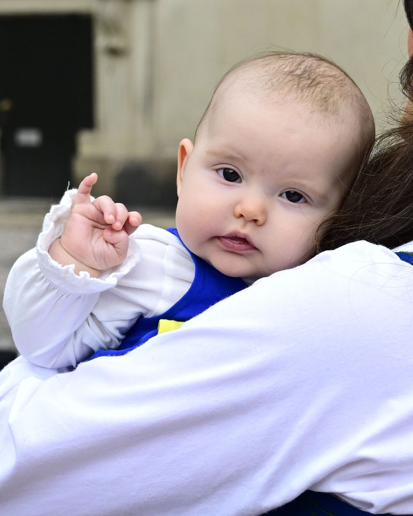 Princess Ines waves in her mother's arms