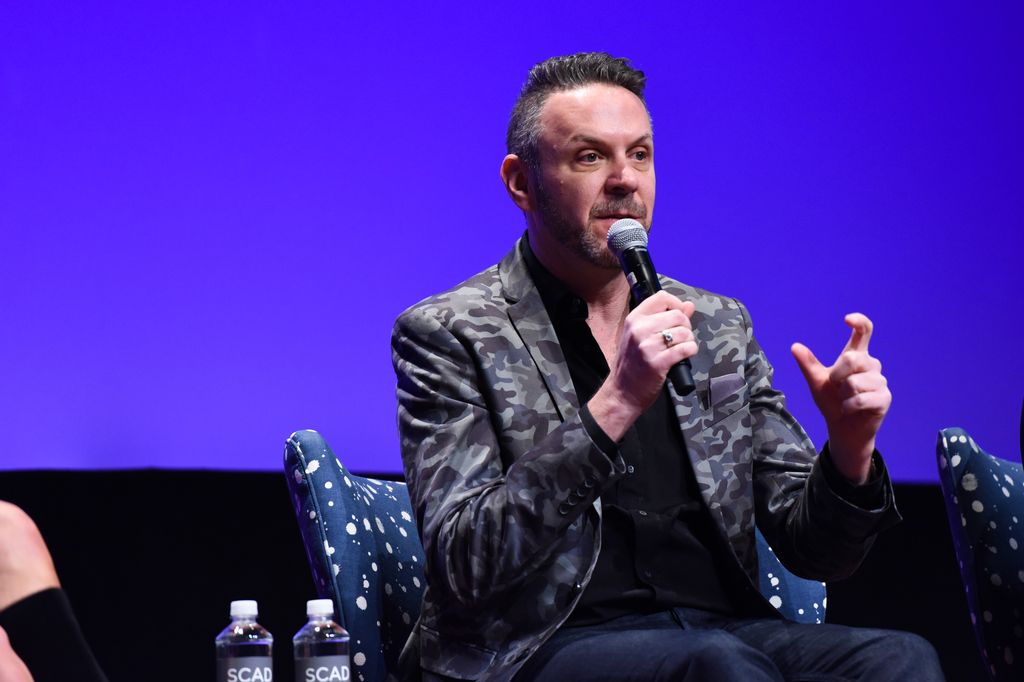 photo of loren ruch on stage holding a mircophone
