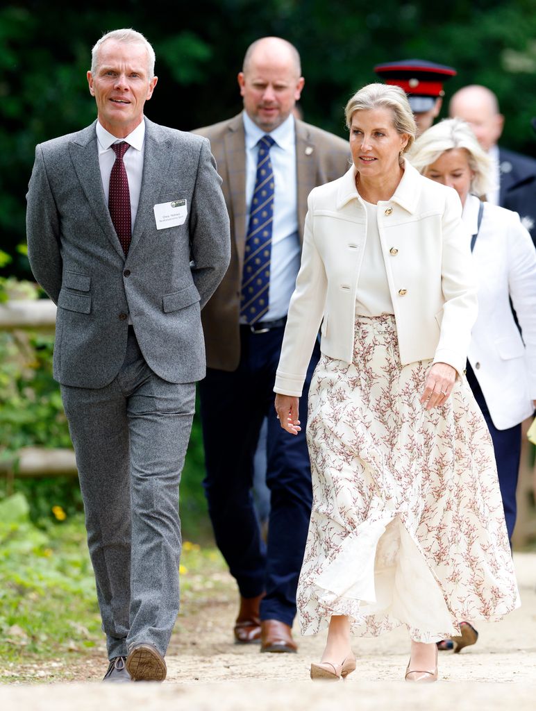 Sophie, Duchess of Edinburgh accompanied by Chris Holmes walking in white outfit