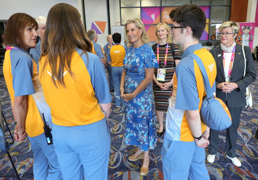 Sophie, smiles as she speaks with staff members in blue and yellow outfits
