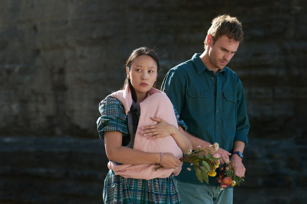 woman holding baby walking alongside man