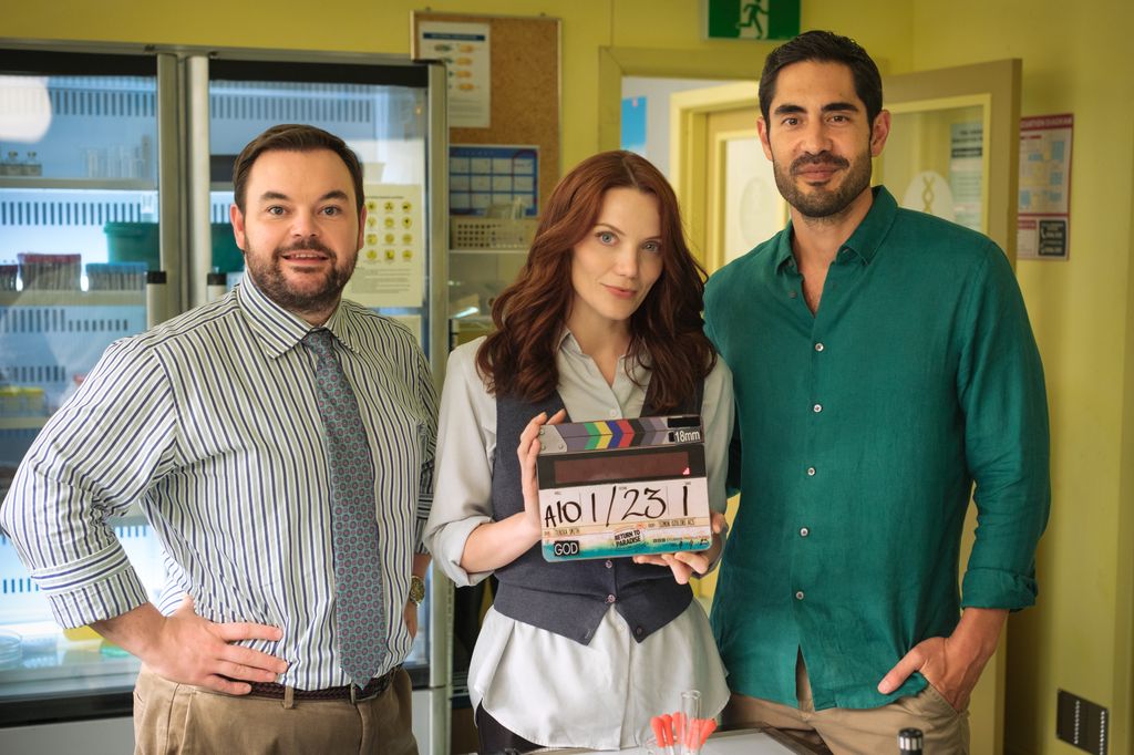 two men and woman on tv set holding clapper board