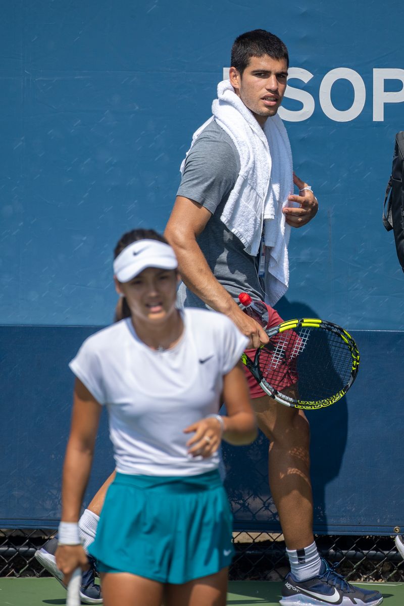 NEW YORK, USA, August 26. Carlos Alcaraz of Spain walks past Emma Raducanu of Great Britain during her practice session in preparation for the US Open Tennis Championship 2022 at the USTA National Tennis Centre on August 26th 2022 in Flushing, Queens, New York City.  (Photo by Tim Clayton/Corbis via Getty Images)