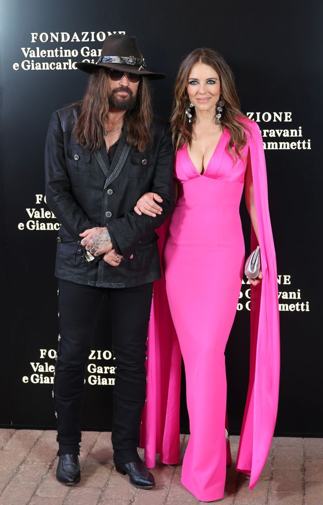 Billy Ray Cyrus and Elizabeth Hurley poses in pink dress
