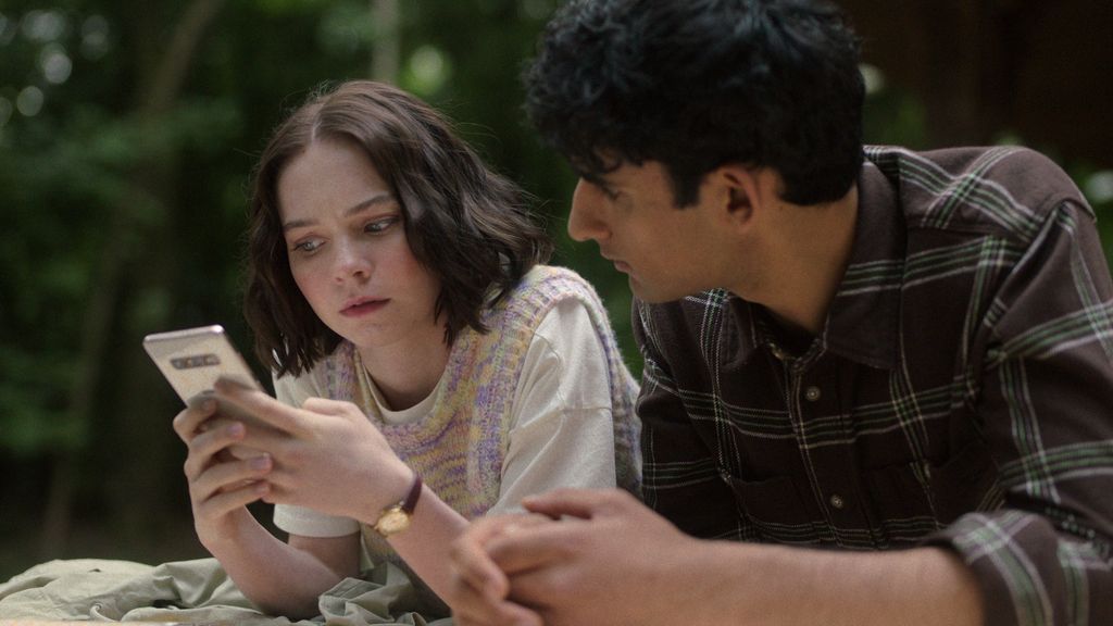 woman and boy lying on ground looking at phone