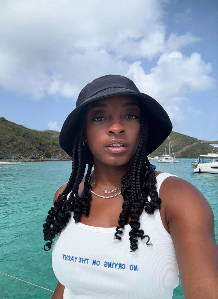 Photo shared by Simone Biles on Instagram July 2025 aboard a yacht, wearing a white tank top and black bucket hat