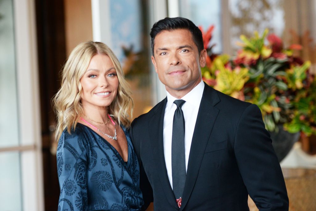 kelly ripa posing with mark consuelos in front of flowers