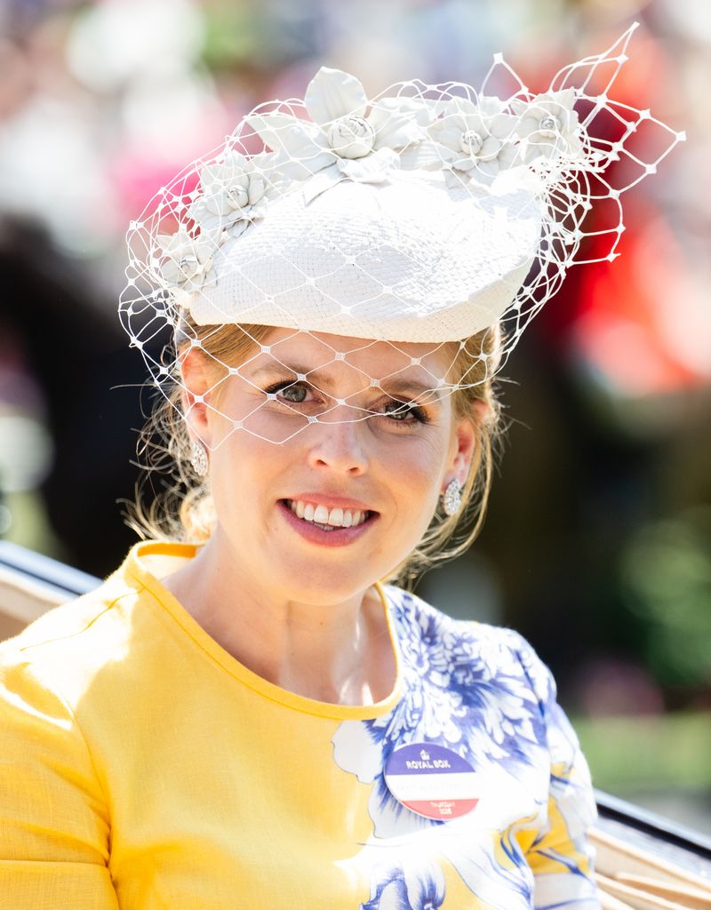 Princess Beatrice smiling in yellow dress and net hat
