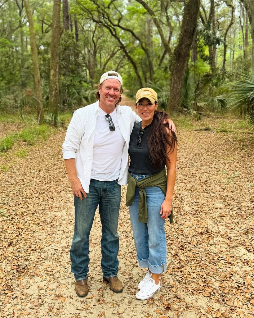 Chip and Joanna Gaines wrap their arms around each other as they stand in the woods