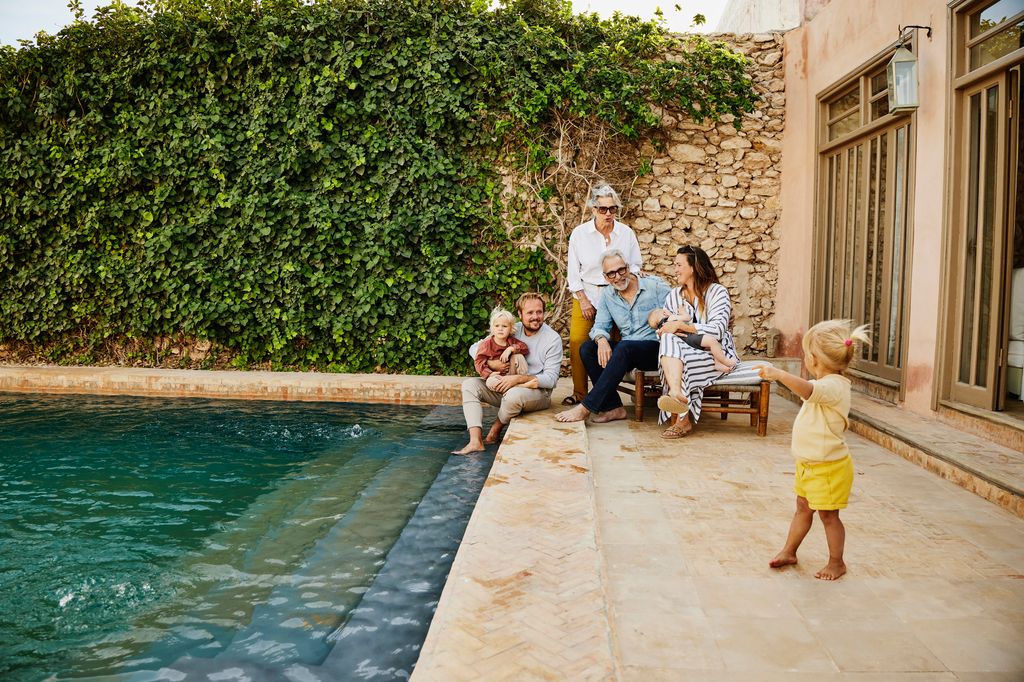 Wide shot smiling multigenerational family relaxing at tropical villa