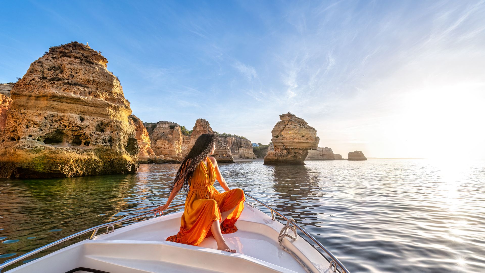 A woman on a boat sailing near rock formations