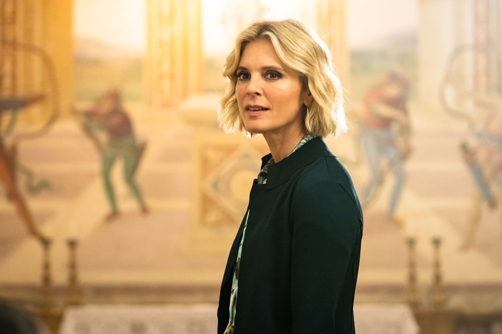 blonde woman standing in front of painting