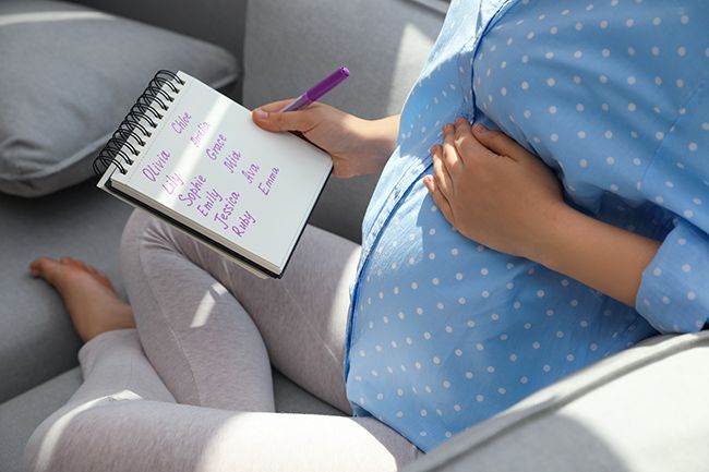A pregnant woman writing a list of baby names