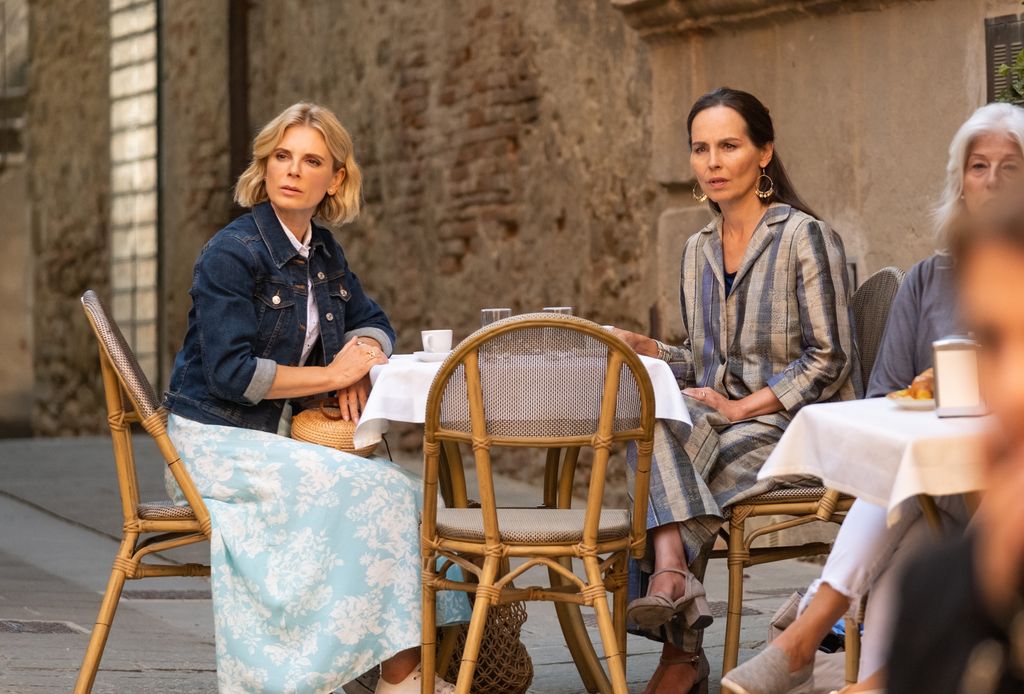 two women sitting at table in street