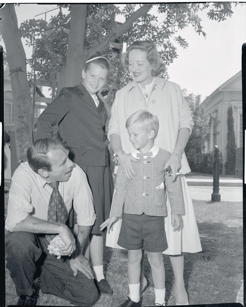 Returning to the studio where she made her first picture 25 years before, Bette Davis wishes her husband Gary Merrill, good luck on the first day of work in his new film. Looking on are the Merrills' children, Barbara, nicknamed "B.D.,", 10, and Mike, 5. Merrill was costarring in C. V. Whitney's The Missouri Traveler, being filmed at the Warner Brother's Studios, where Miss Davis gained two Academy Awards.