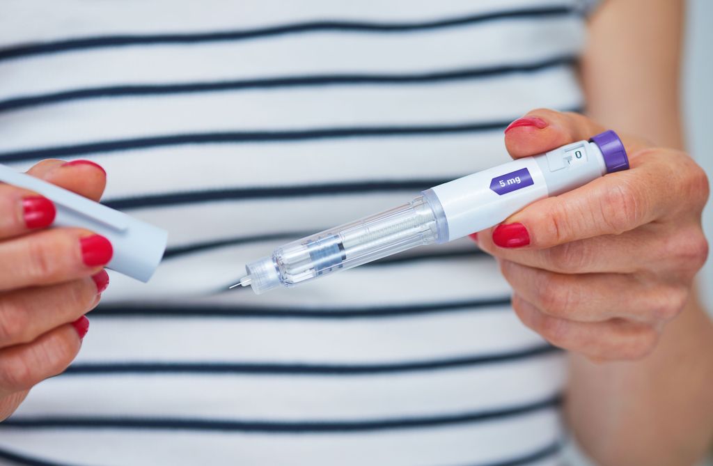 Woman using injection pen to administer weight loss drug -