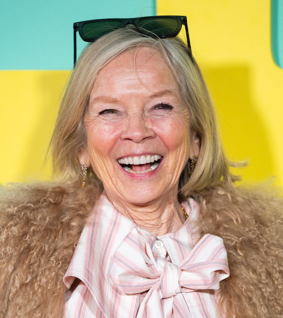 Jo Wood in a fluffy coat and striped blouse smiling widely