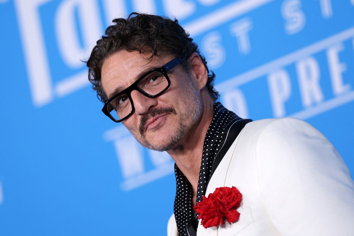 Pedro Pascal dressed in a white dinner jacket by Haider Ackermann for Tom Ford, featuring a red carnation.