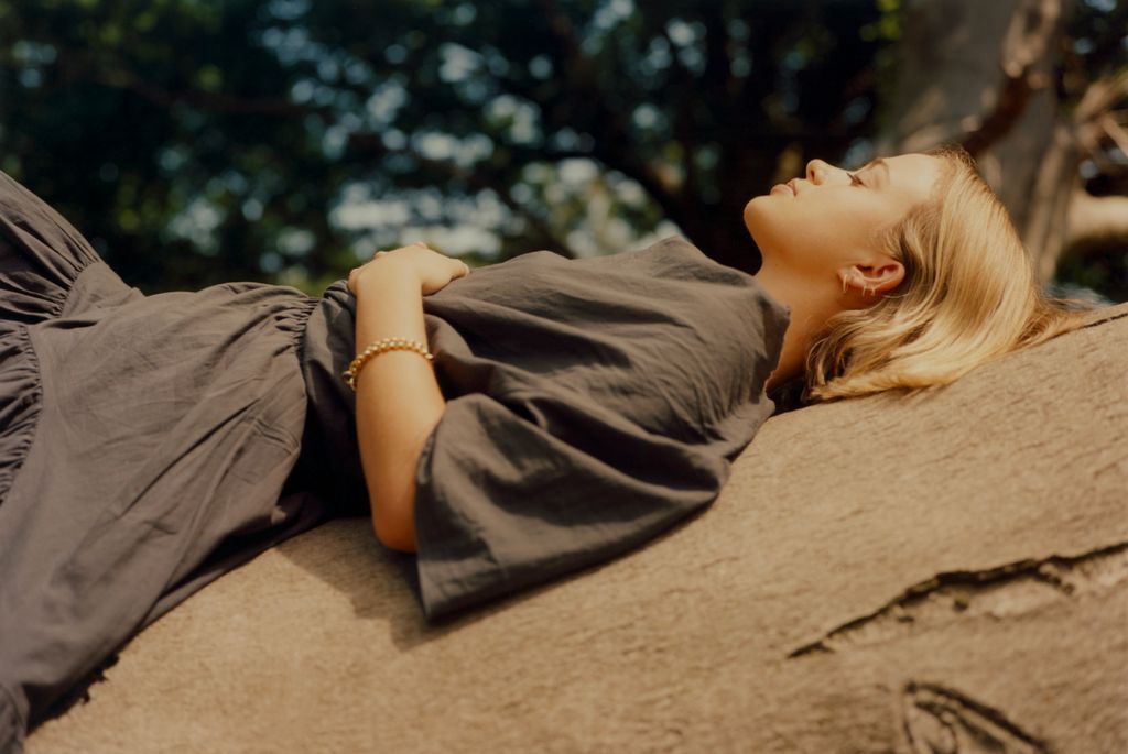 amelia widsor in a black dress lying on a tree