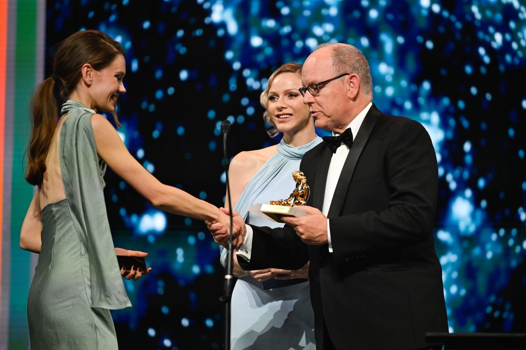 albert and charlene presenting someone with an award on stage 