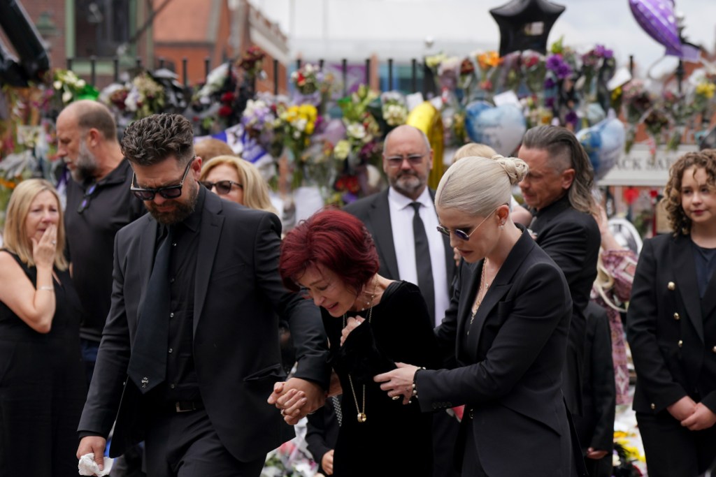 The family of Ozzy Osbourne (left to right) Jack, Sharon and Kelly Osbourne, view the messages and floral tributes left at the Black Sabbath Bridge bench on Broad Street in Birmingham in memory of Black Sabbath frontman Ozzy Osbourne, as his body is brought back to his home city for a procession following his death last week aged 76. Picture date: Wednesday July 30, 2025. Photo credit should read: Joe Giddens/PA Wire (Photo by Joe Giddens/PA Images via Getty Images)