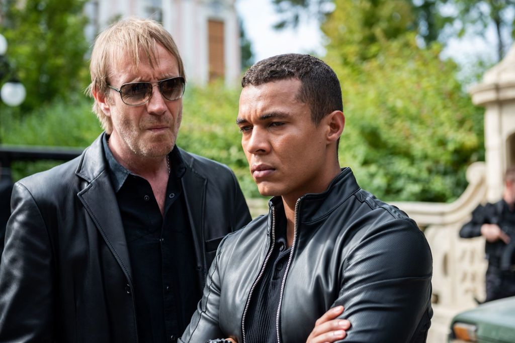two men dressed in black standing in street