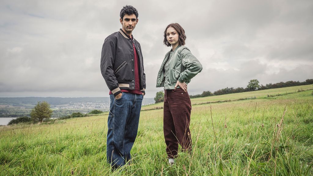 two teens standing in field