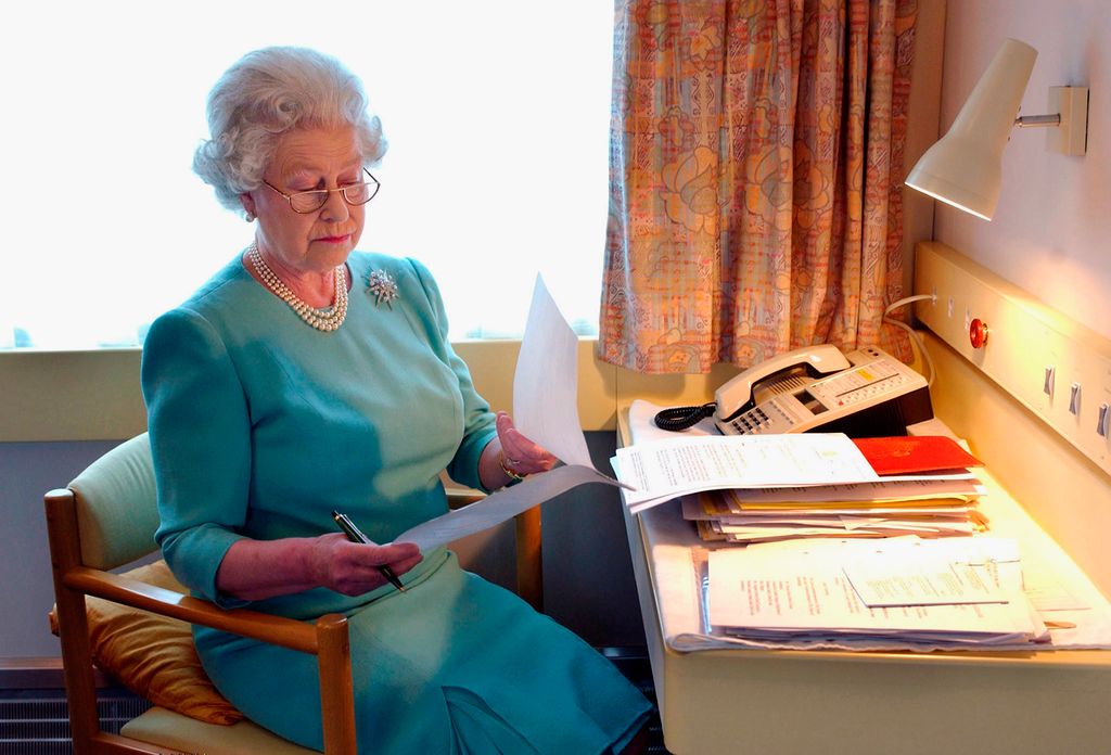 Queen Elizabeth II looking at papers at her desk on the royal train